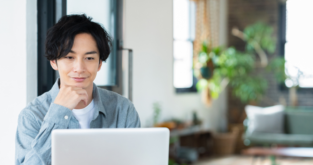 パソコンの画面を見ながら笑顔を浮かべる男性
